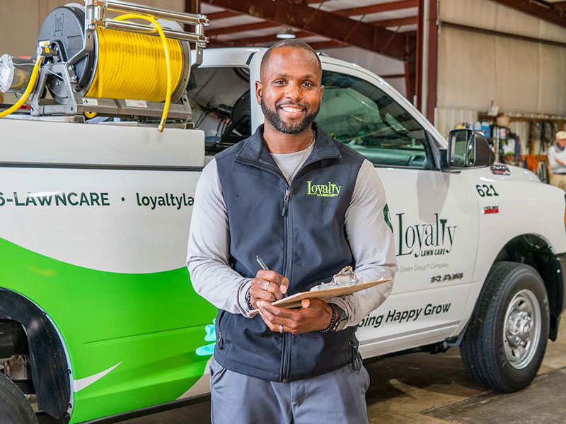 Man standing in front of a Loyalty Lawn Care themed truck.