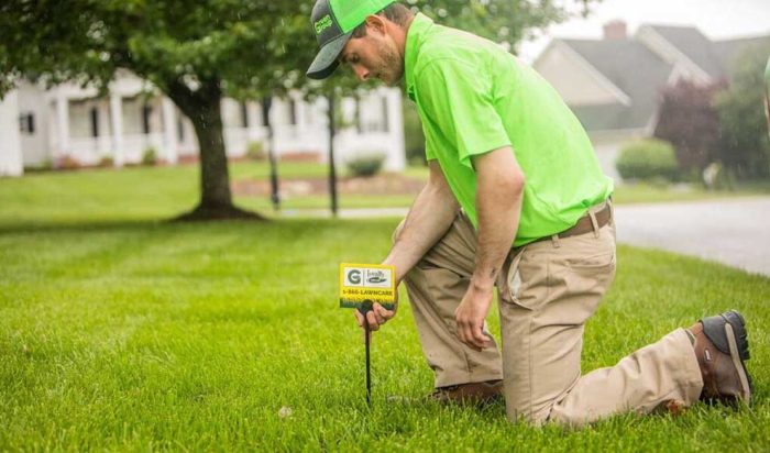 A Loyalty Lawn Care worker placing a branded lawn care yard sign.