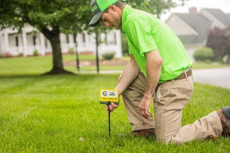 title-photo-fertilization-weed-control A Loyalty Lawn Care worker placing a branded lawn care yard sign.