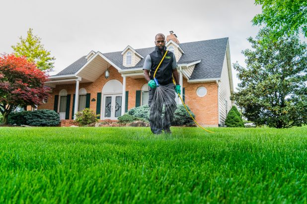 A Loyalty Lawn Care spraying the grass with a hose.